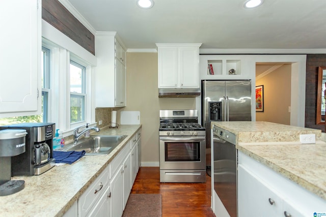 kitchen with dark wood-type flooring, sink, ornamental molding, stainless steel appliances, and white cabinets