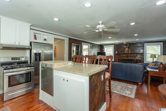 kitchen featuring a kitchen island, appliances with stainless steel finishes, dark hardwood / wood-style floors, a fireplace, and white cabinets