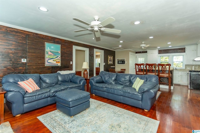 living room with crown molding, ceiling fan, and dark wood-type flooring