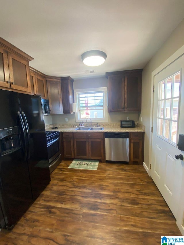 kitchen featuring light stone counters, black appliances, sink, and dark hardwood / wood-style flooring