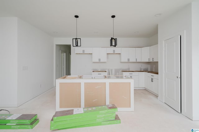 kitchen with a kitchen island with sink, white cabinets, and decorative light fixtures