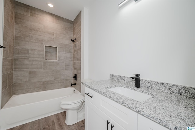 full bathroom featuring toilet, vanity, hardwood / wood-style flooring, and tiled shower / bath combo