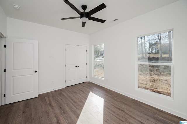 unfurnished bedroom with multiple windows, dark hardwood / wood-style flooring, and ceiling fan