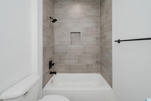 bathroom featuring tiled shower / bath combo and toilet