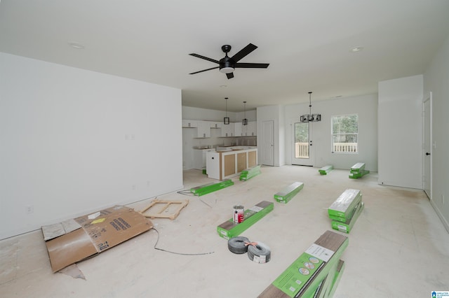 unfurnished living room featuring ceiling fan with notable chandelier