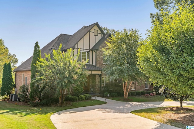 english style home with a front yard and central air condition unit