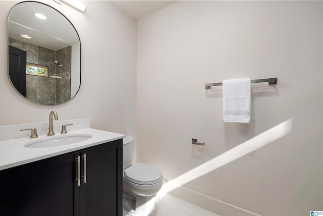 bathroom featuring tile patterned flooring, a tile shower, vanity, and toilet