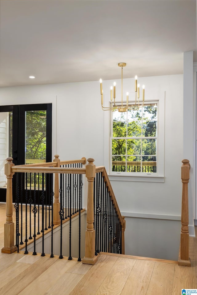 stairs featuring hardwood / wood-style flooring and a notable chandelier