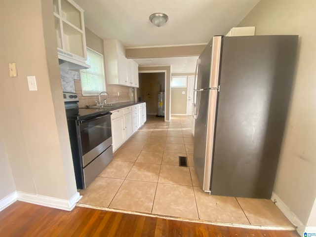 kitchen featuring appliances with stainless steel finishes, light wood-type flooring, backsplash, and white cabinets