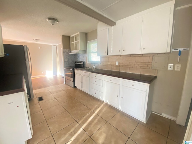 kitchen with electric stove, white cabinets, light tile patterned floors, and sink