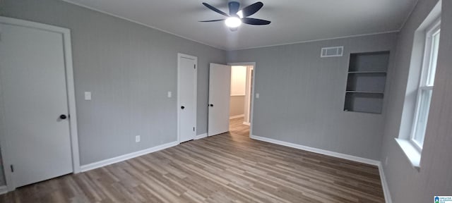 unfurnished bedroom featuring hardwood / wood-style flooring, ceiling fan, and multiple windows