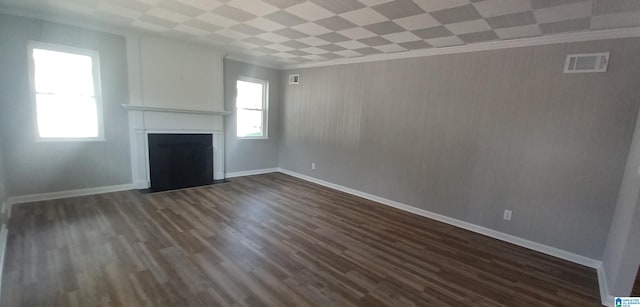 unfurnished living room featuring crown molding, dark wood-type flooring, and a wealth of natural light