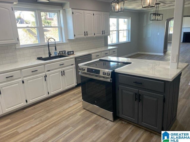 kitchen with white cabinetry, sink, hanging light fixtures, and electric stove