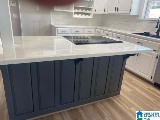 kitchen featuring white cabinetry, sink, light stone counters, and light hardwood / wood-style floors