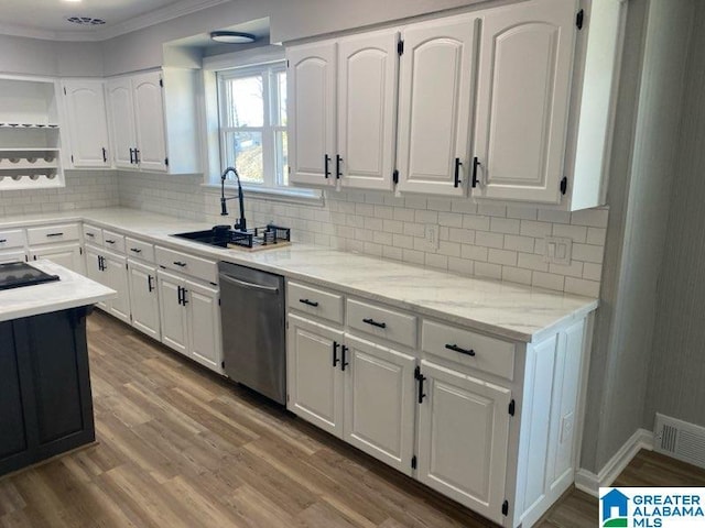 kitchen featuring hardwood / wood-style floors, white cabinetry, sink, decorative backsplash, and stainless steel dishwasher