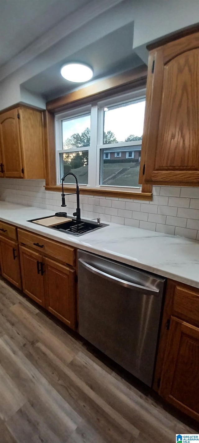 kitchen featuring tasteful backsplash, wood-type flooring, sink, stainless steel dishwasher, and plenty of natural light