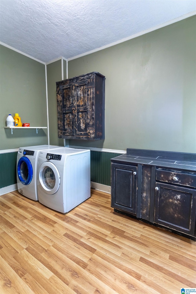 laundry area with a textured ceiling, light wood-type flooring, crown molding, and washing machine and clothes dryer