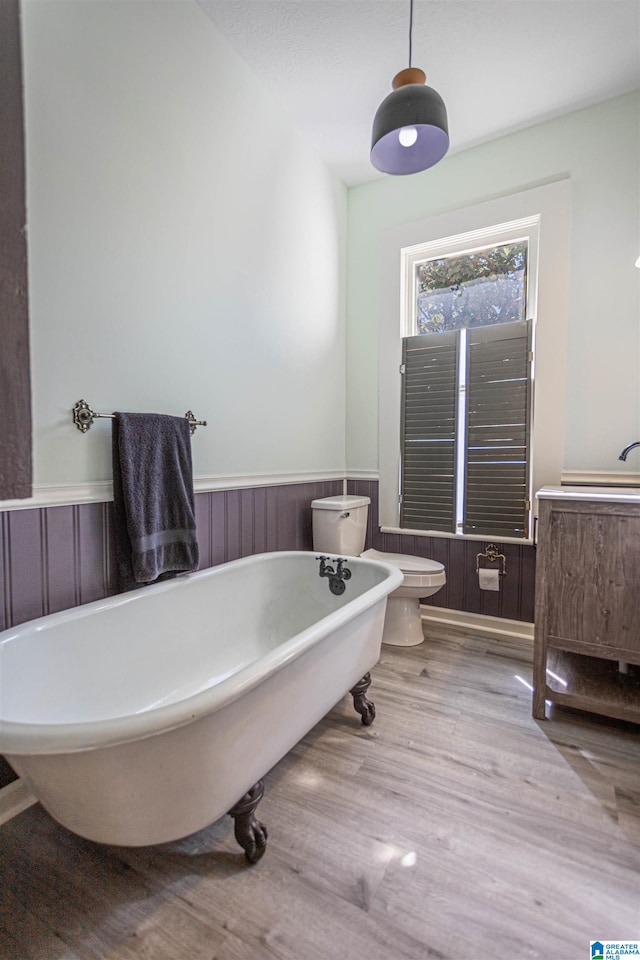 bathroom with wood-type flooring, wooden walls, toilet, and a tub