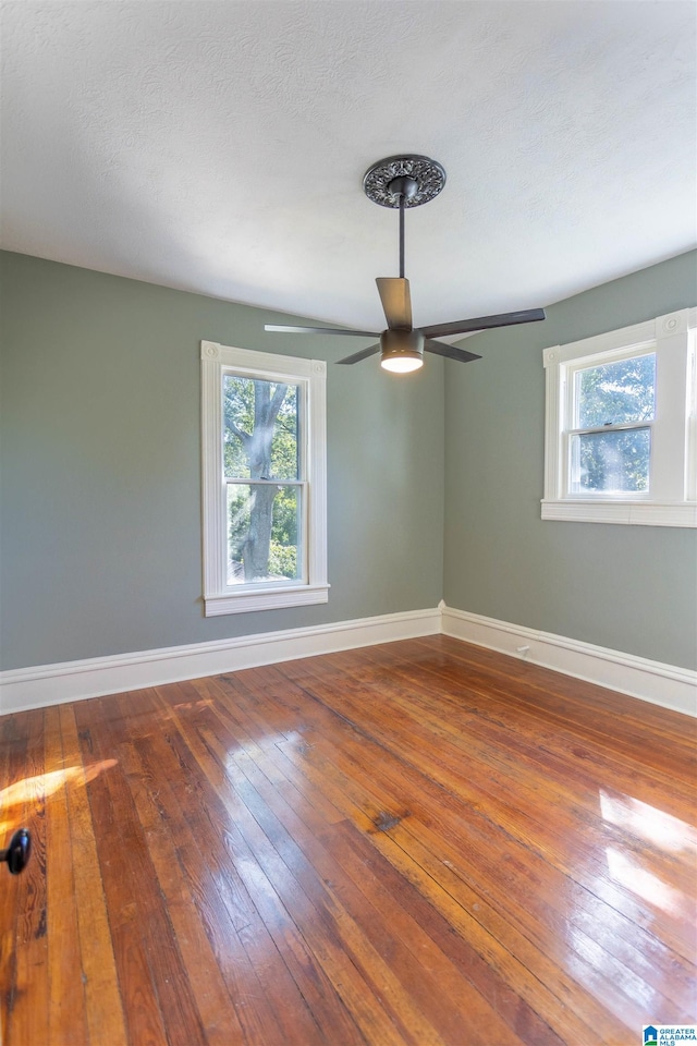 empty room with hardwood / wood-style flooring, a textured ceiling, and ceiling fan