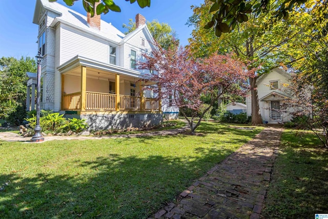 view of side of property with a lawn and covered porch