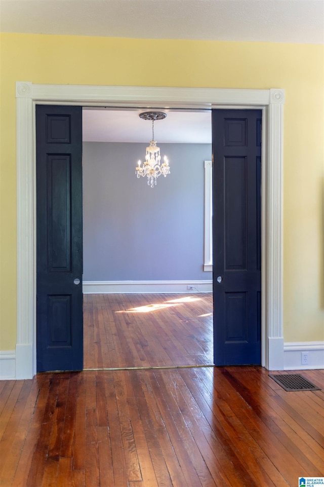 unfurnished dining area with a chandelier and dark wood-type flooring