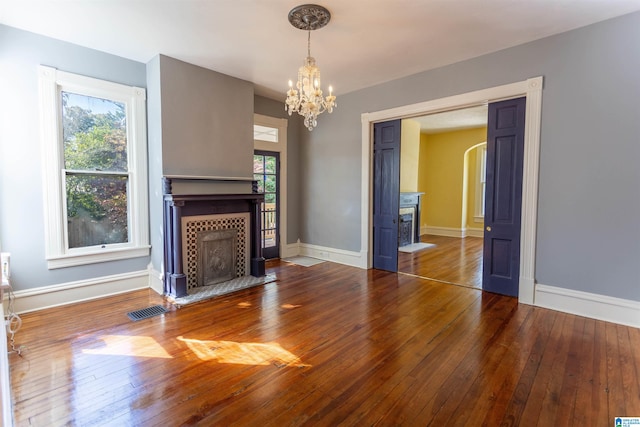 unfurnished living room featuring plenty of natural light, hardwood / wood-style floors, and an inviting chandelier