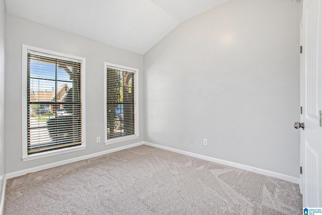 spare room featuring lofted ceiling and light carpet