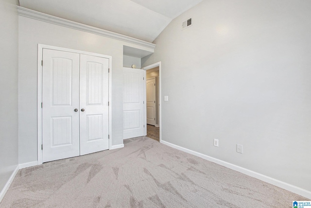 unfurnished bedroom featuring a closet, light colored carpet, and vaulted ceiling