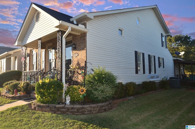 property exterior at dusk featuring a lawn