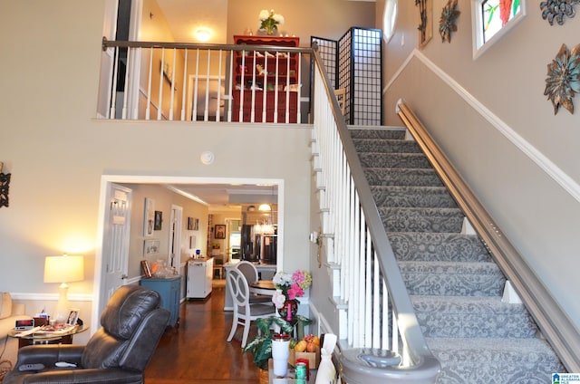 stairs featuring a high ceiling, hardwood / wood-style flooring, and crown molding