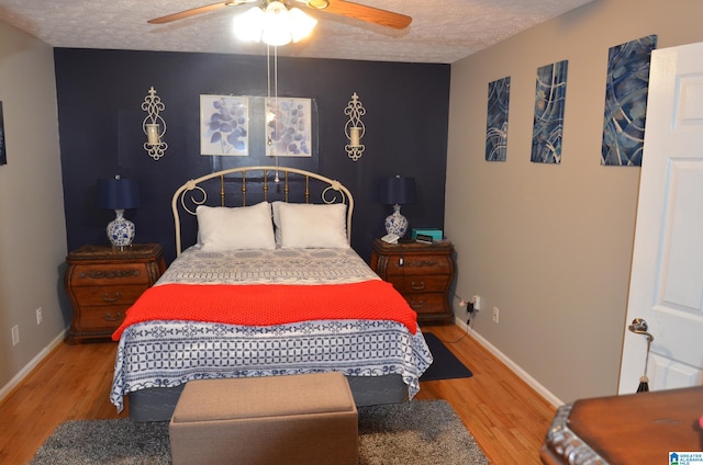 bedroom with hardwood / wood-style flooring, ceiling fan, and a textured ceiling