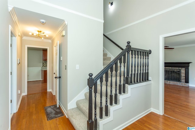 staircase featuring a fireplace, ornamental molding, and hardwood / wood-style floors