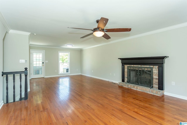 unfurnished living room with a brick fireplace, crown molding, hardwood / wood-style flooring, and ceiling fan