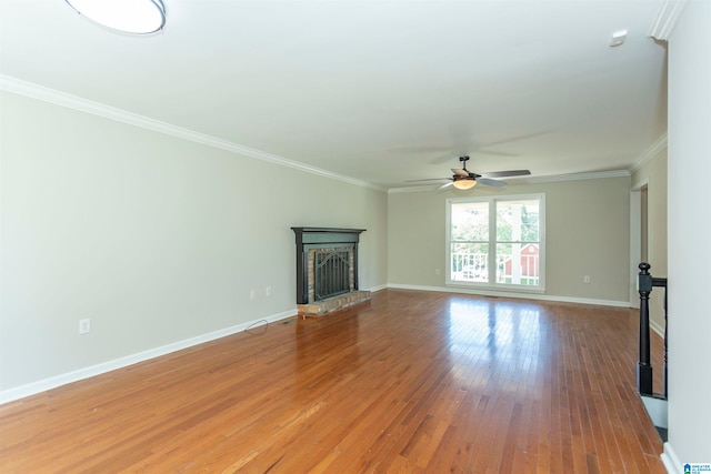 unfurnished living room with a brick fireplace, crown molding, wood-type flooring, and ceiling fan