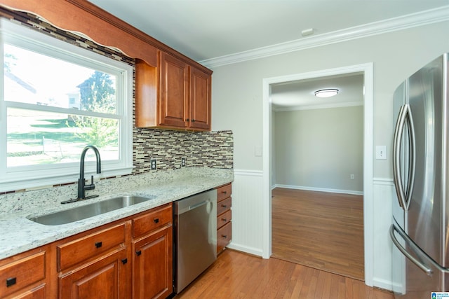 kitchen featuring light wood-type flooring, sink, stainless steel appliances, light stone countertops, and ornamental molding