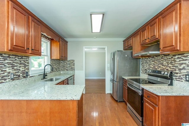 kitchen featuring light stone counters, ornamental molding, sink, appliances with stainless steel finishes, and light wood-type flooring