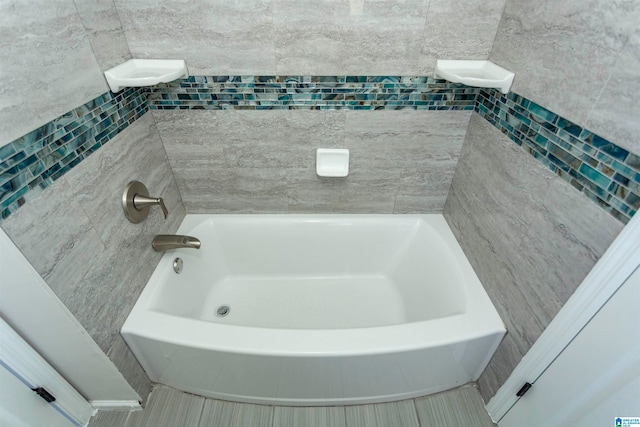 bathroom with a tub to relax in, tile walls, and tile patterned floors