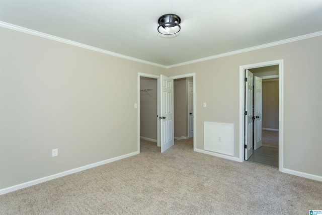 unfurnished bedroom with a spacious closet, ornamental molding, a closet, and light carpet