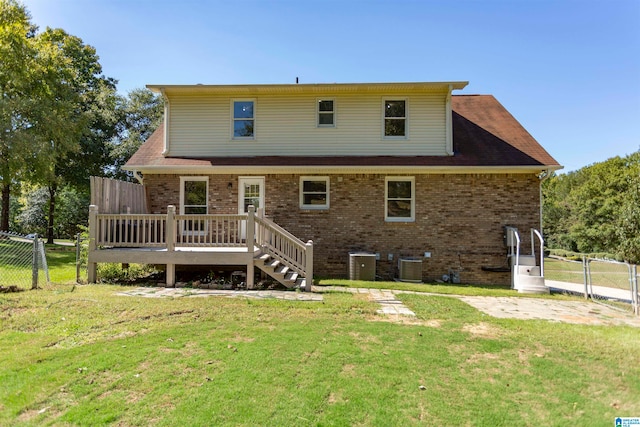 rear view of property with cooling unit, a wooden deck, and a lawn