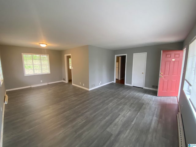 unfurnished room featuring dark wood-type flooring and baseboard heating