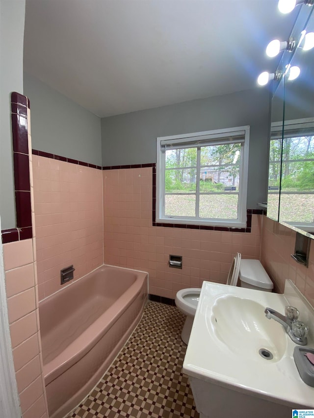 bathroom featuring sink, tile walls, toilet, and a bath