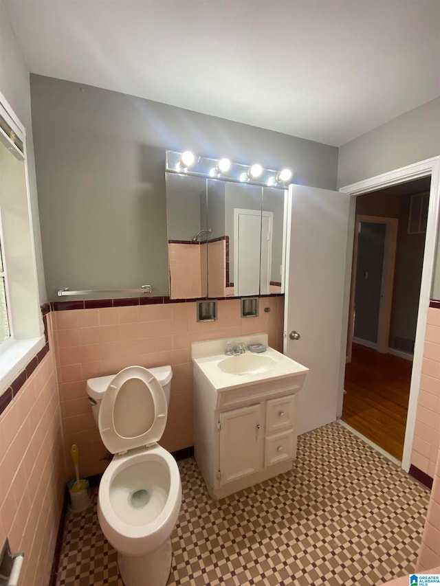 bathroom with vanity, tile walls, and toilet