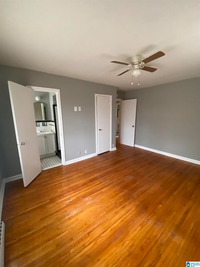 unfurnished bedroom featuring wood-type flooring, ensuite bathroom, and ceiling fan