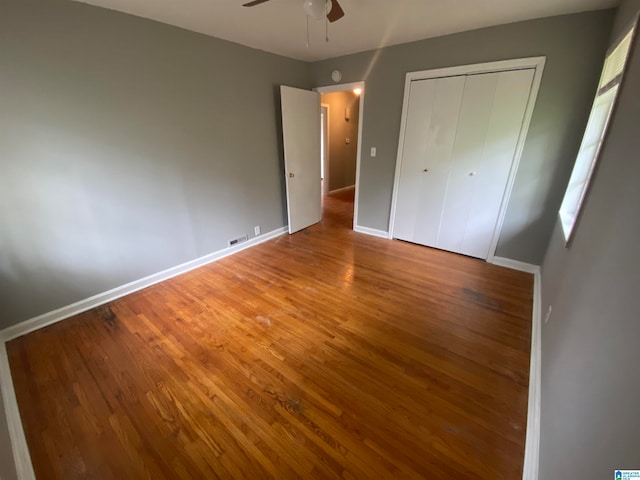 unfurnished bedroom with a closet, hardwood / wood-style flooring, and ceiling fan