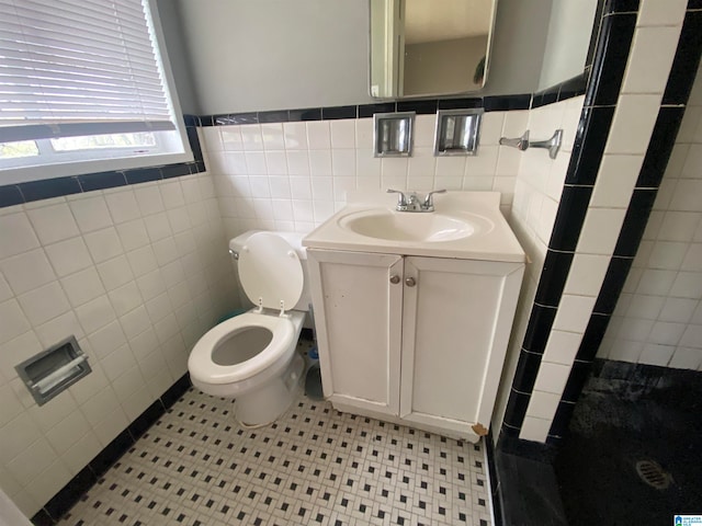 bathroom featuring vanity, tile walls, and toilet