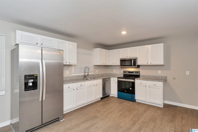 kitchen with stainless steel appliances, light hardwood / wood-style floors, and white cabinetry