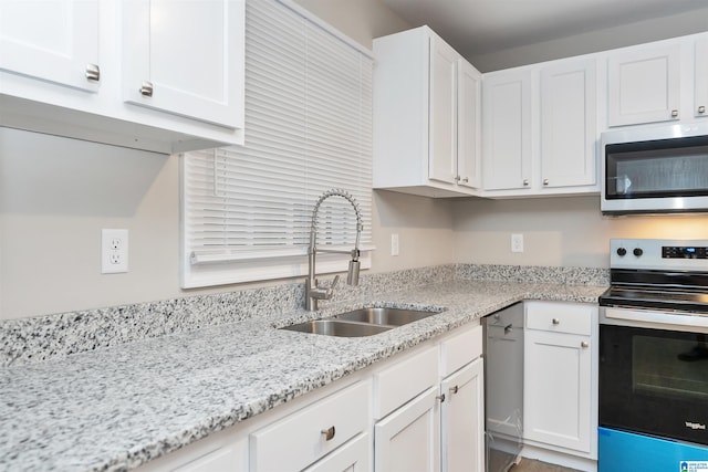 kitchen featuring light stone counters, sink, stainless steel appliances, and white cabinets