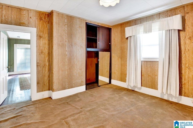 unfurnished bedroom featuring carpet and wooden walls