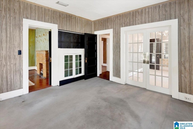 carpeted empty room featuring french doors and wooden walls