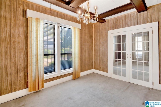 unfurnished room with french doors, a notable chandelier, beamed ceiling, and wooden walls